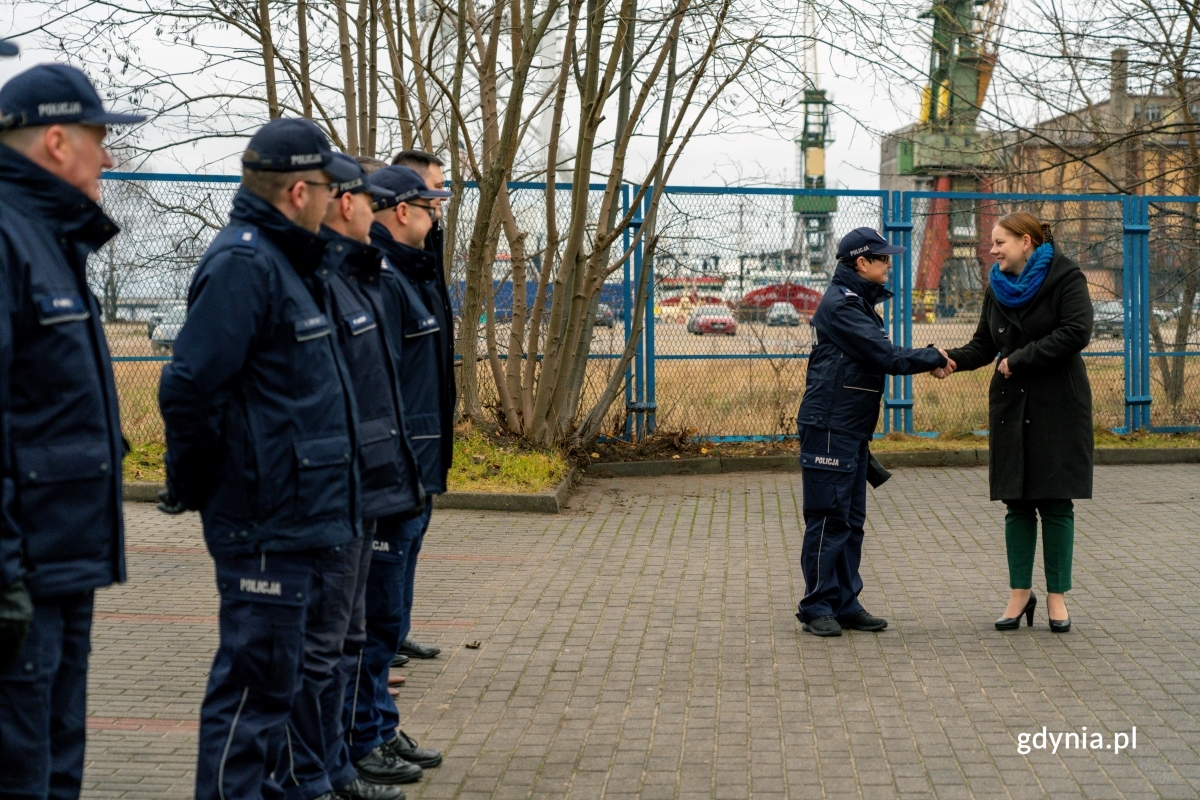 Kobiety podające sobie dłonie i umundurowani policjanci stojący w szeregu